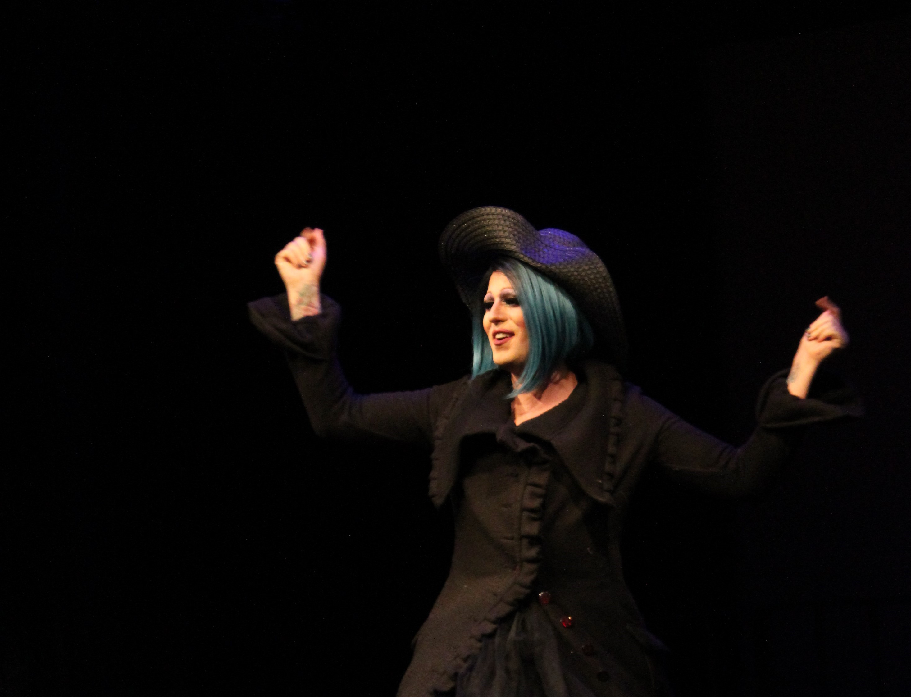 person with long eyelashes in long black dress with blue hair